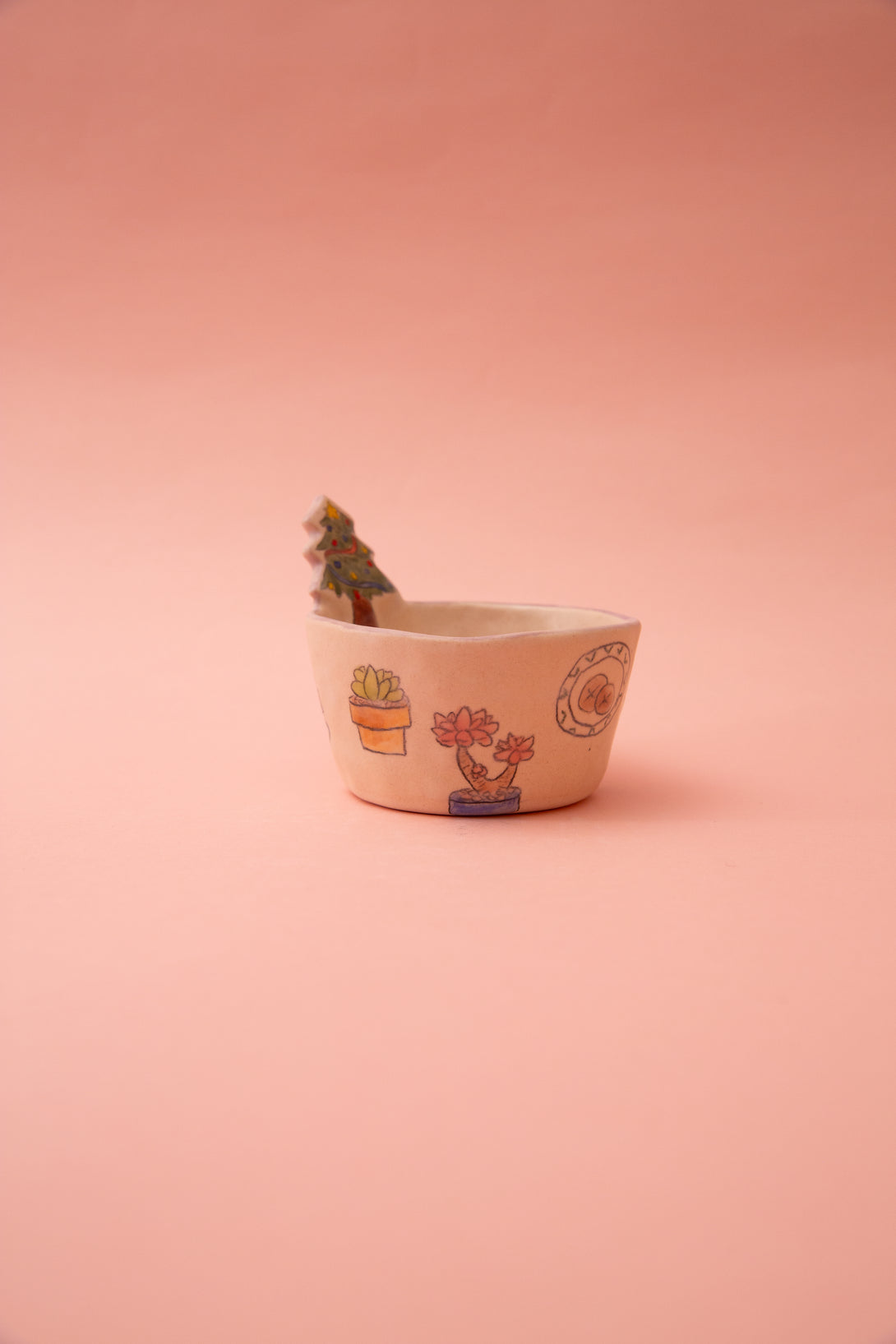 Small ceramic bowl with christmas tree designs on a pink background