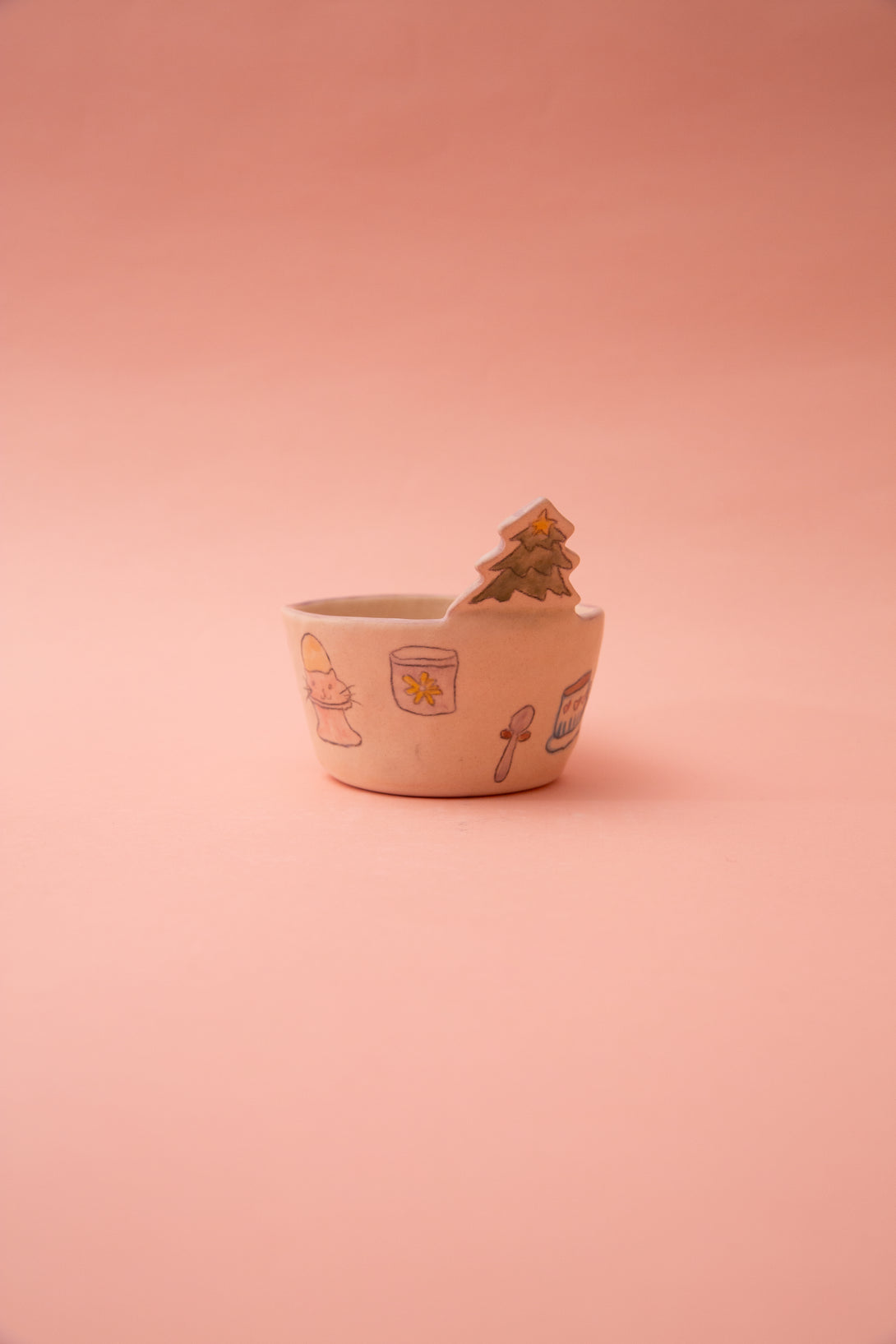 Small ceramic bowl with cartoon designs on a pink background