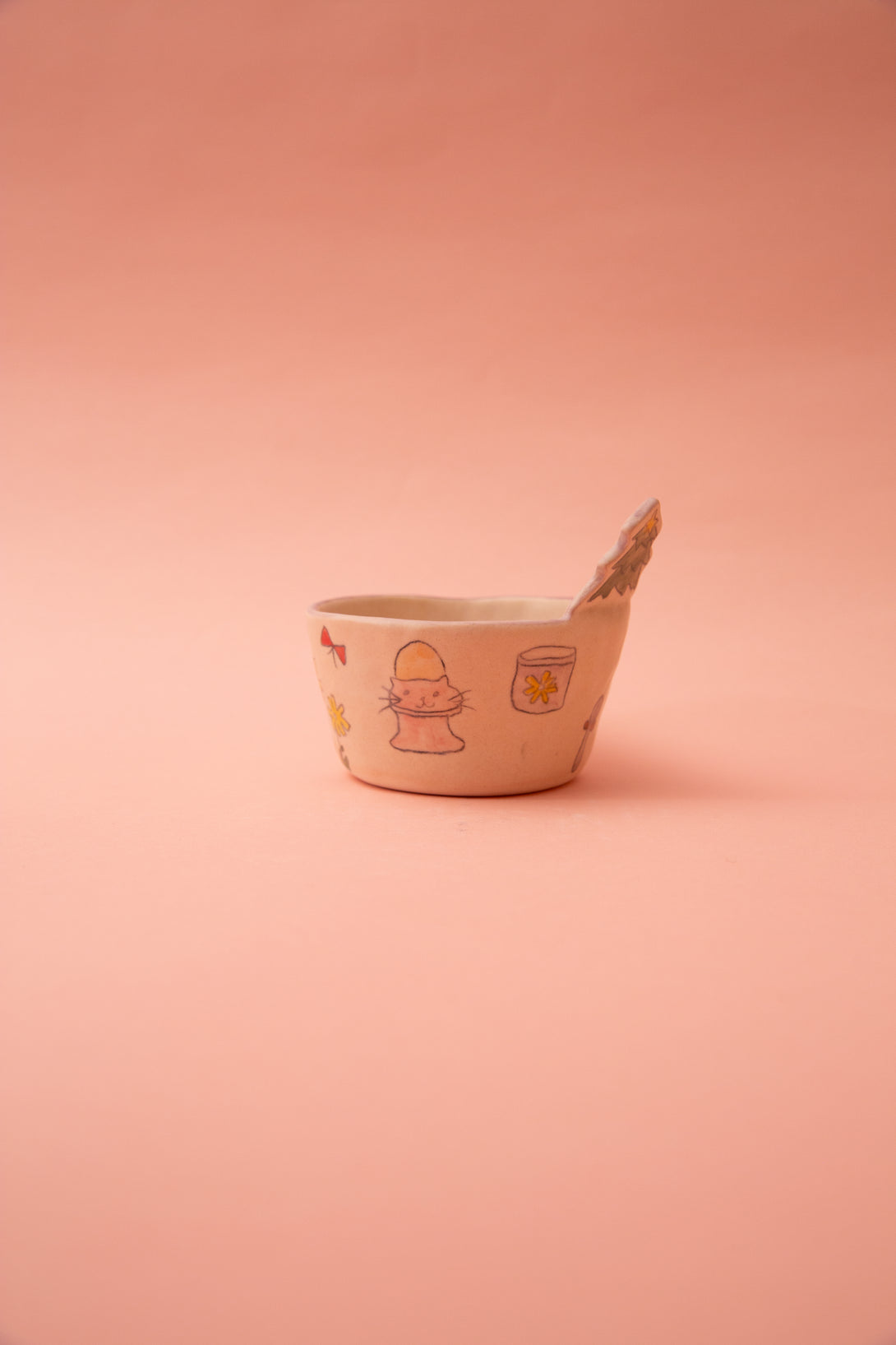 Ceramic mug with cartoon designs on a pink background
