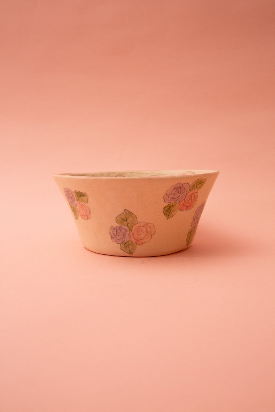 Ceramic bowl with floral designs on a pink background