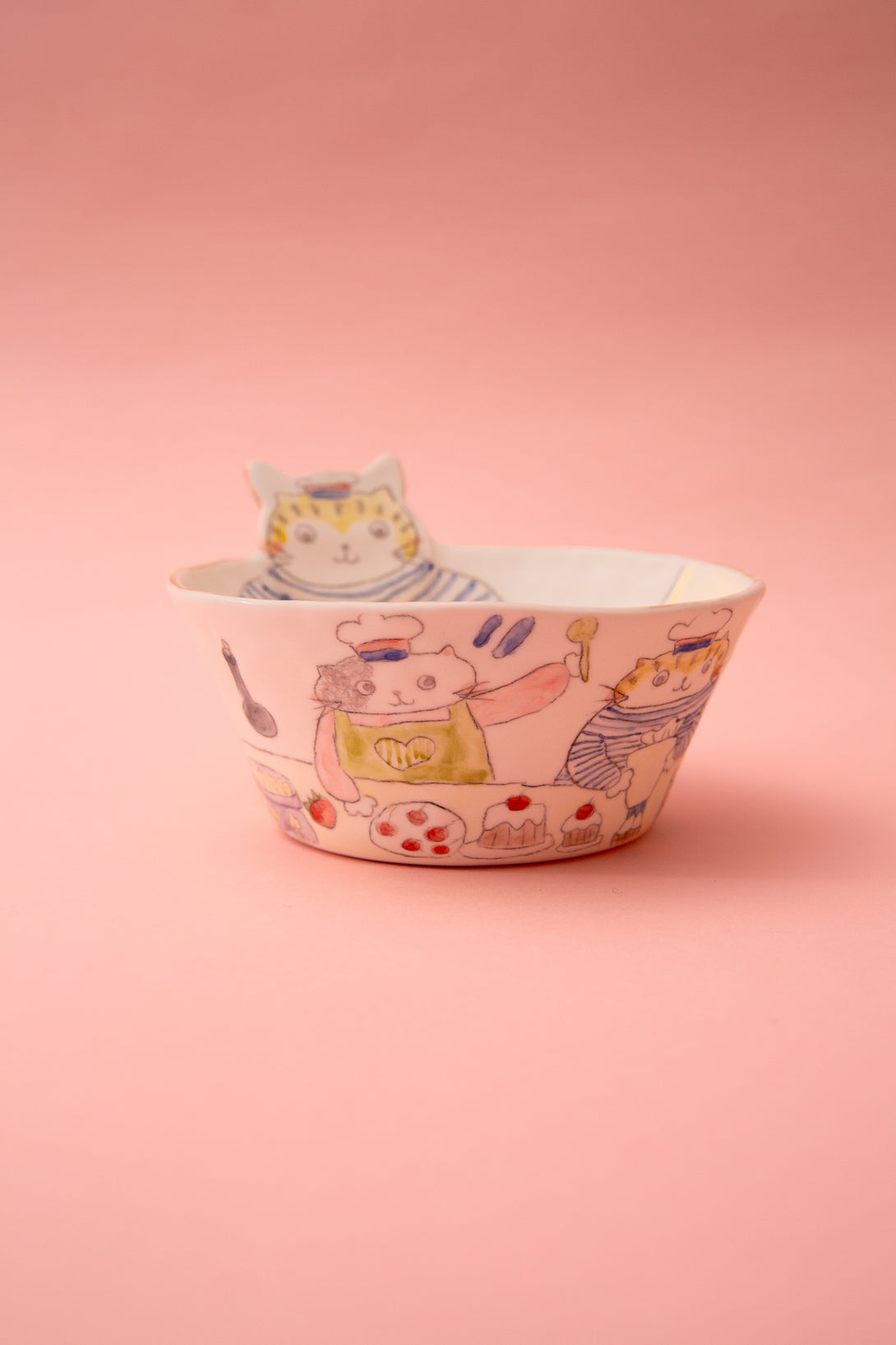 Ceramic bowl with cat illustrations on a pink background