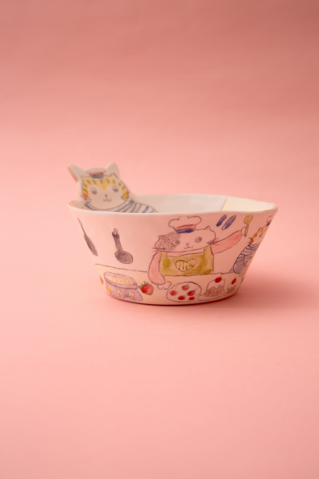 Ceramic bowl with cartoon cat design on a pink background