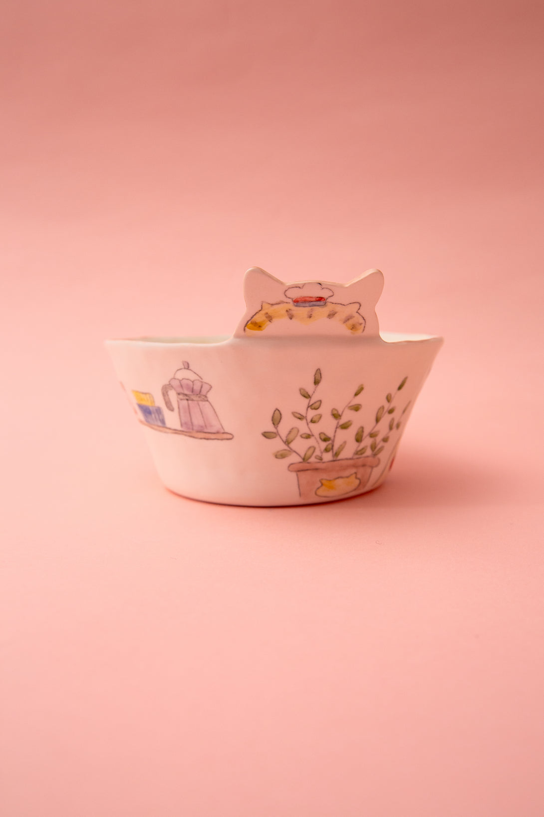 Ceramic bowl with cat ears and illustrations on a pink background