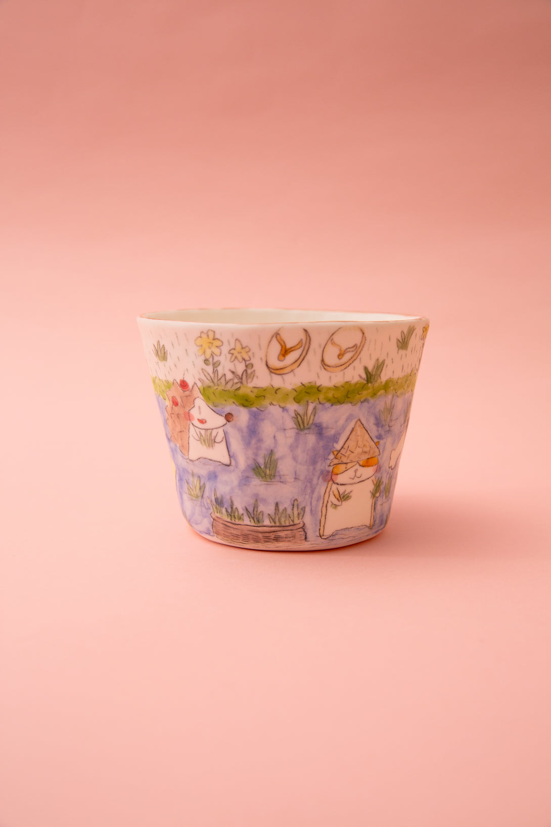 Ceramic mug with cartoon designs on a pink background