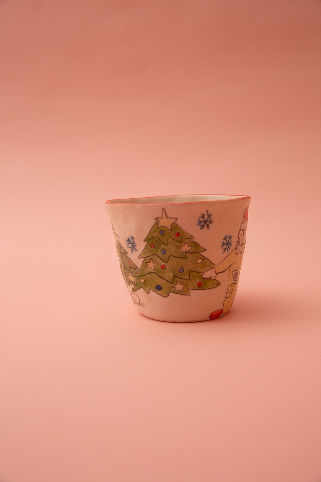 Ceramic cup with Christmas tree design on a pink background