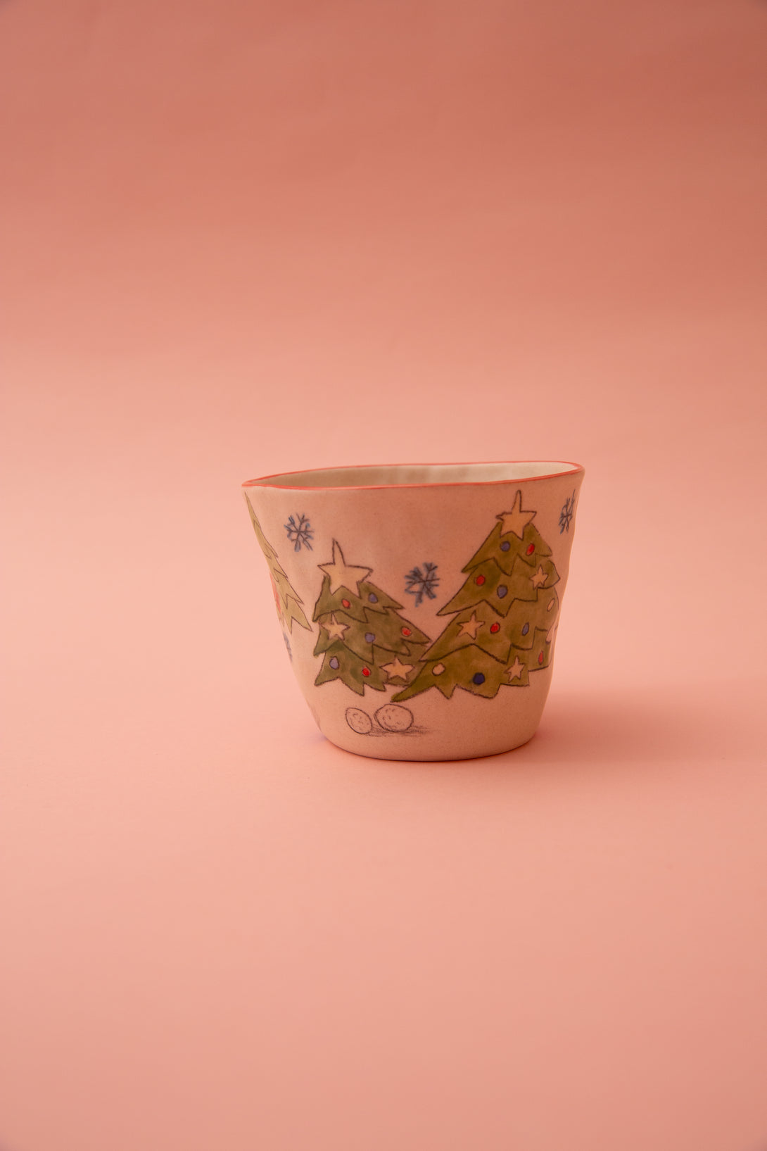 Ceramic cup with Christmas tree design on a pink background