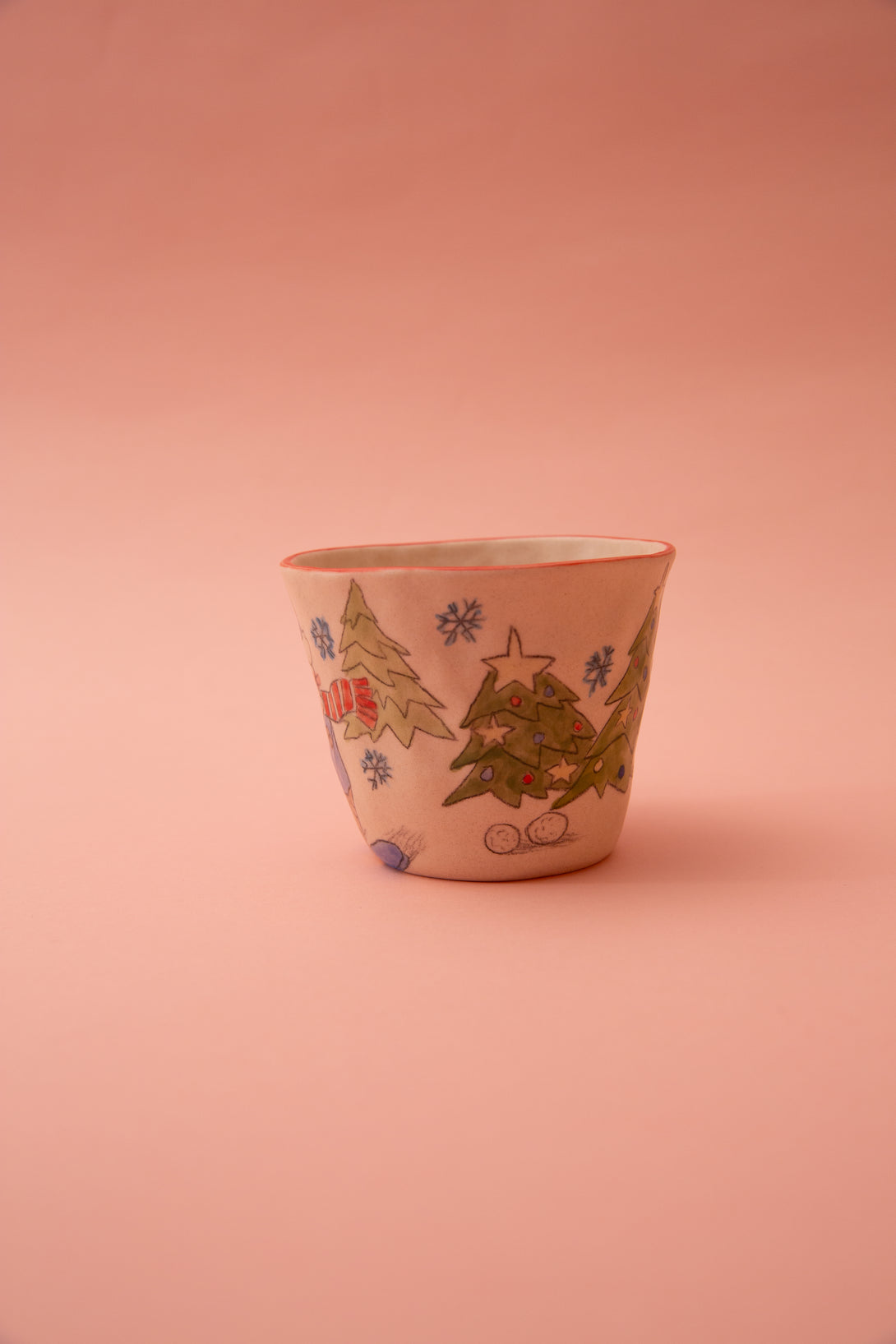 Ceramic cup with Christmas tree designs on a pink background