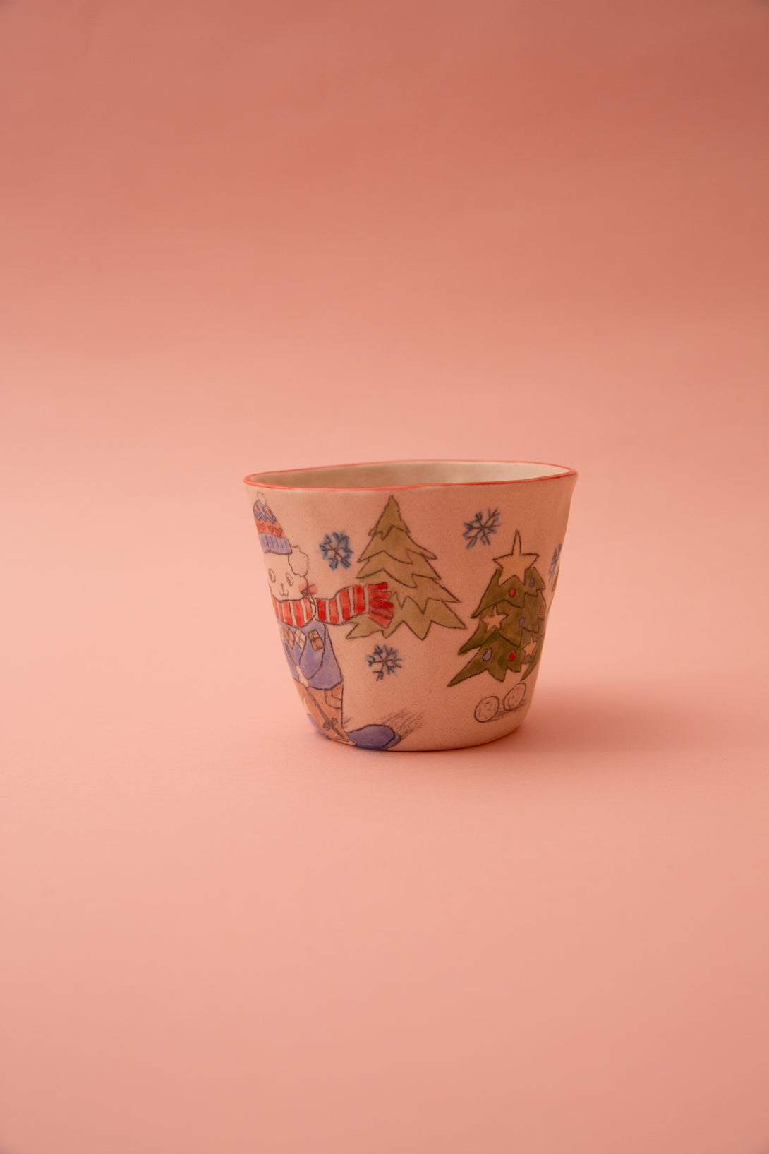 Decorative ceramic cup with Christmas-themed illustrations on a pink background