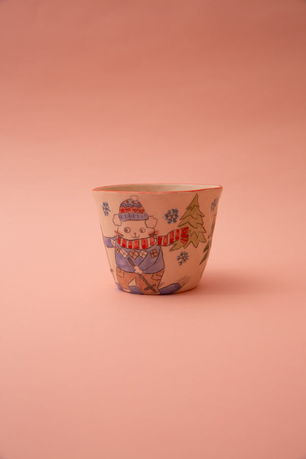 Ceramic cup with a winter-themed design of a cat in a hat and scarf on a pink background