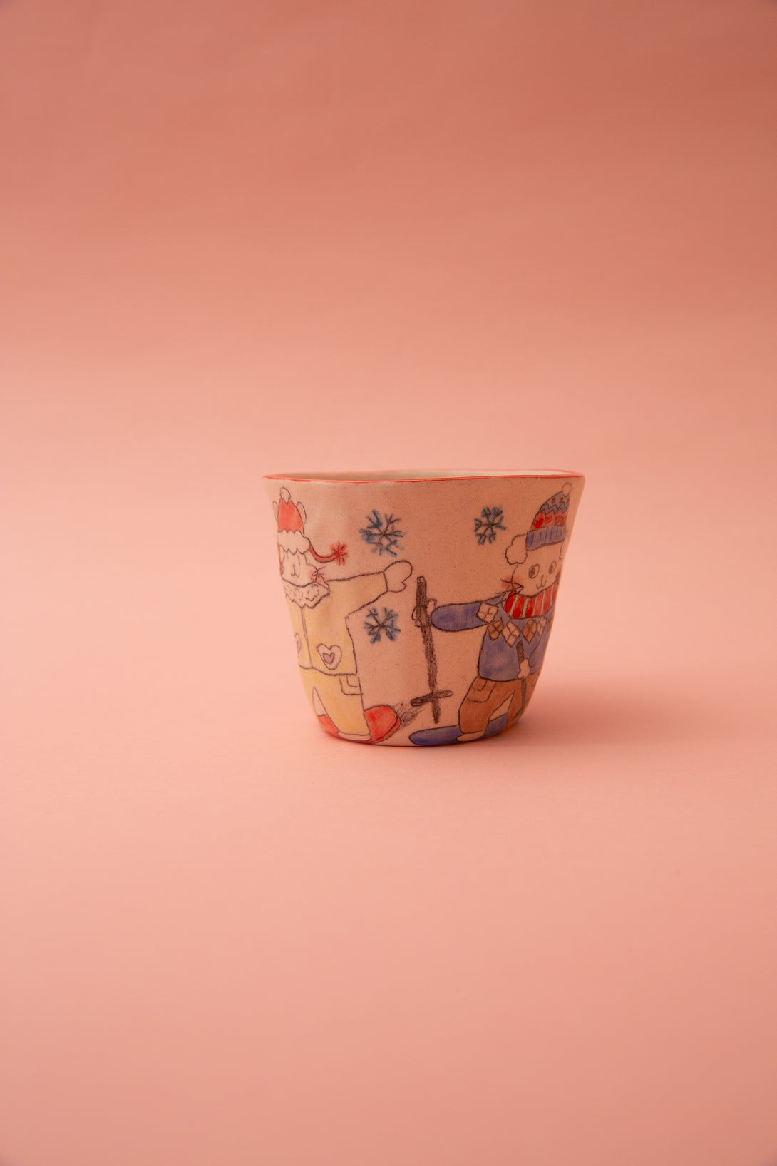 Ceramic cup with winter-themed design on a pink background