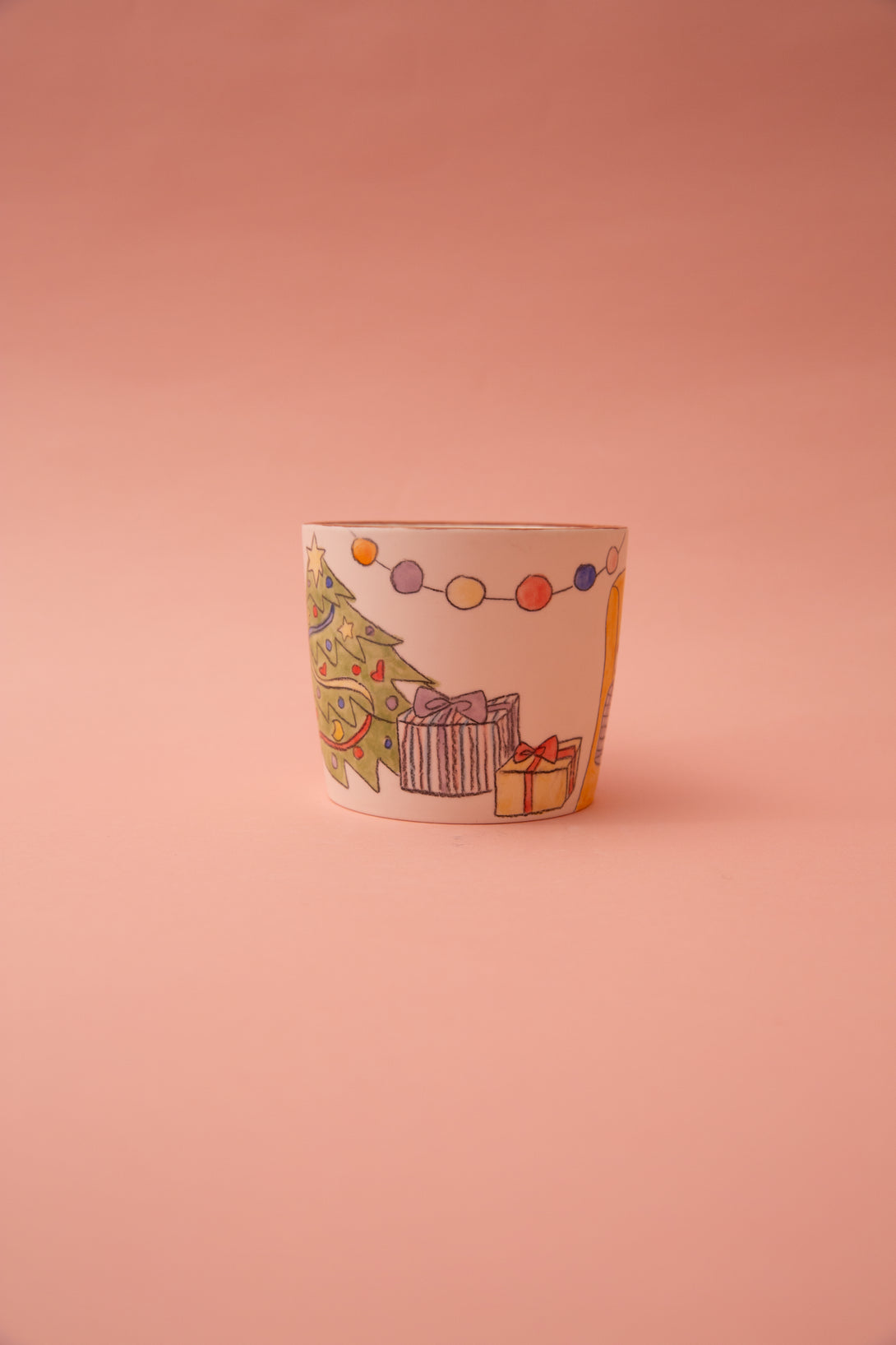 Ceramic mug with Christmas-themed design on a pink background