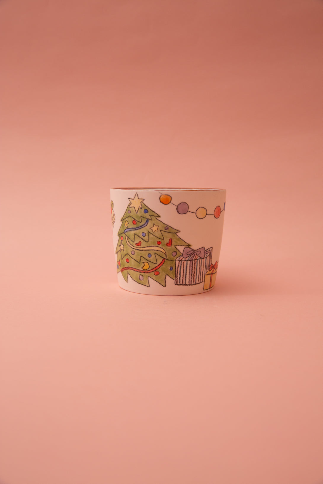Ceramic mug with Christmas tree and gift design on a pink background