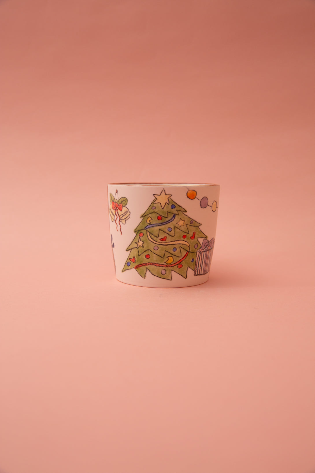 Ceramic mug with a Christmas tree design on a pink background