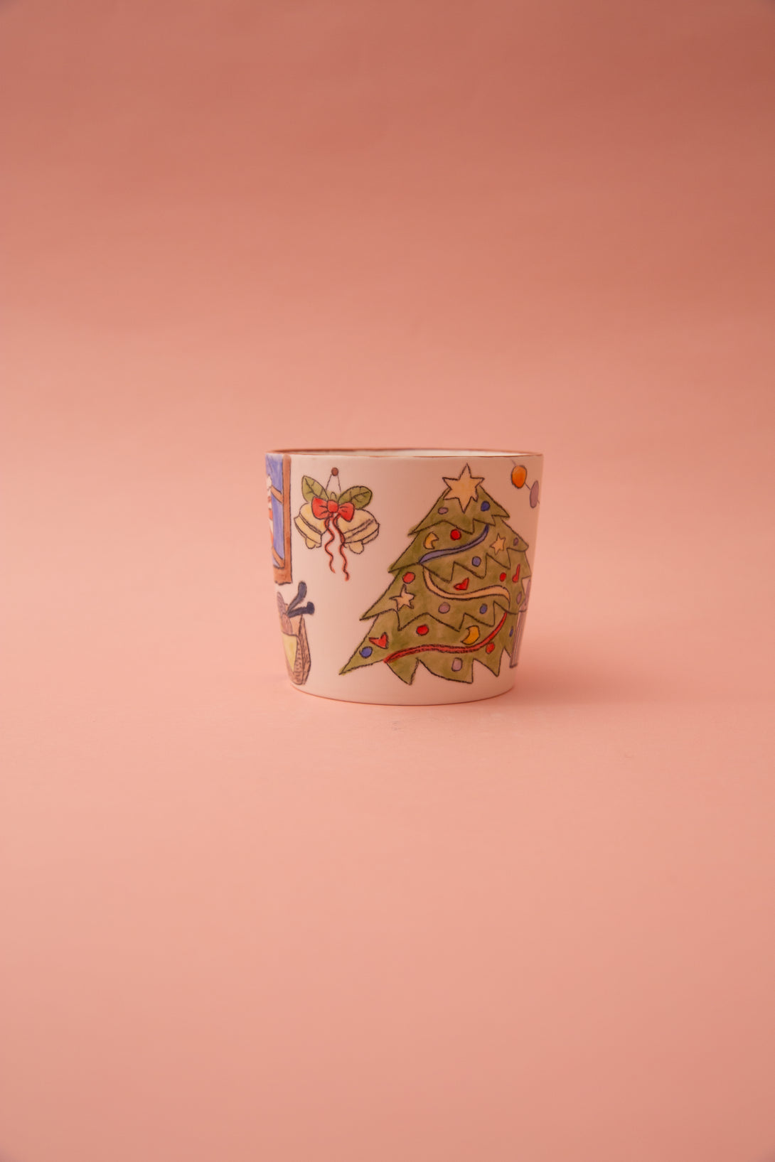 Ceramic mug with a Christmas tree and a bell design on a pink background