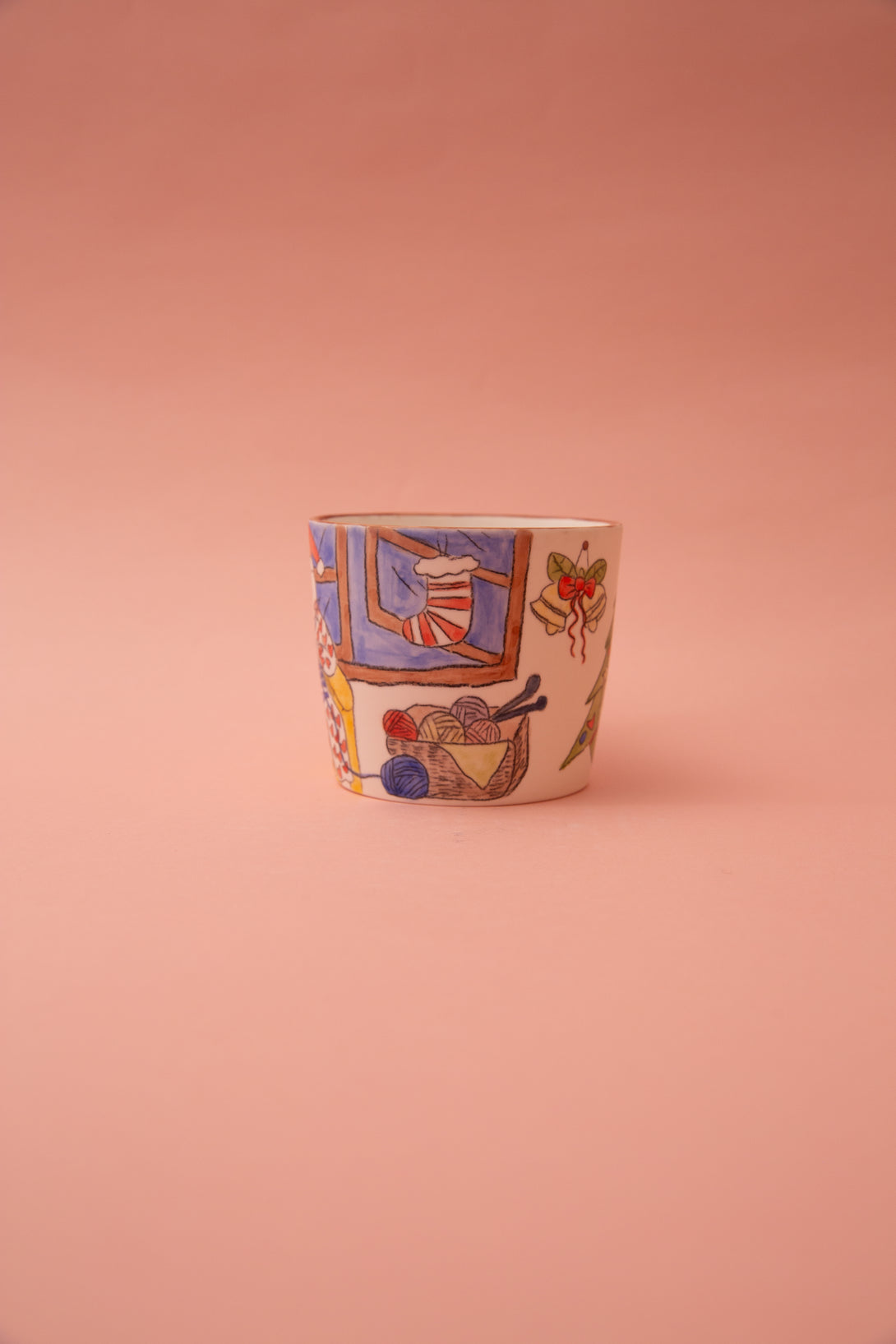 Ceramic cup with colorful designs on a pink background