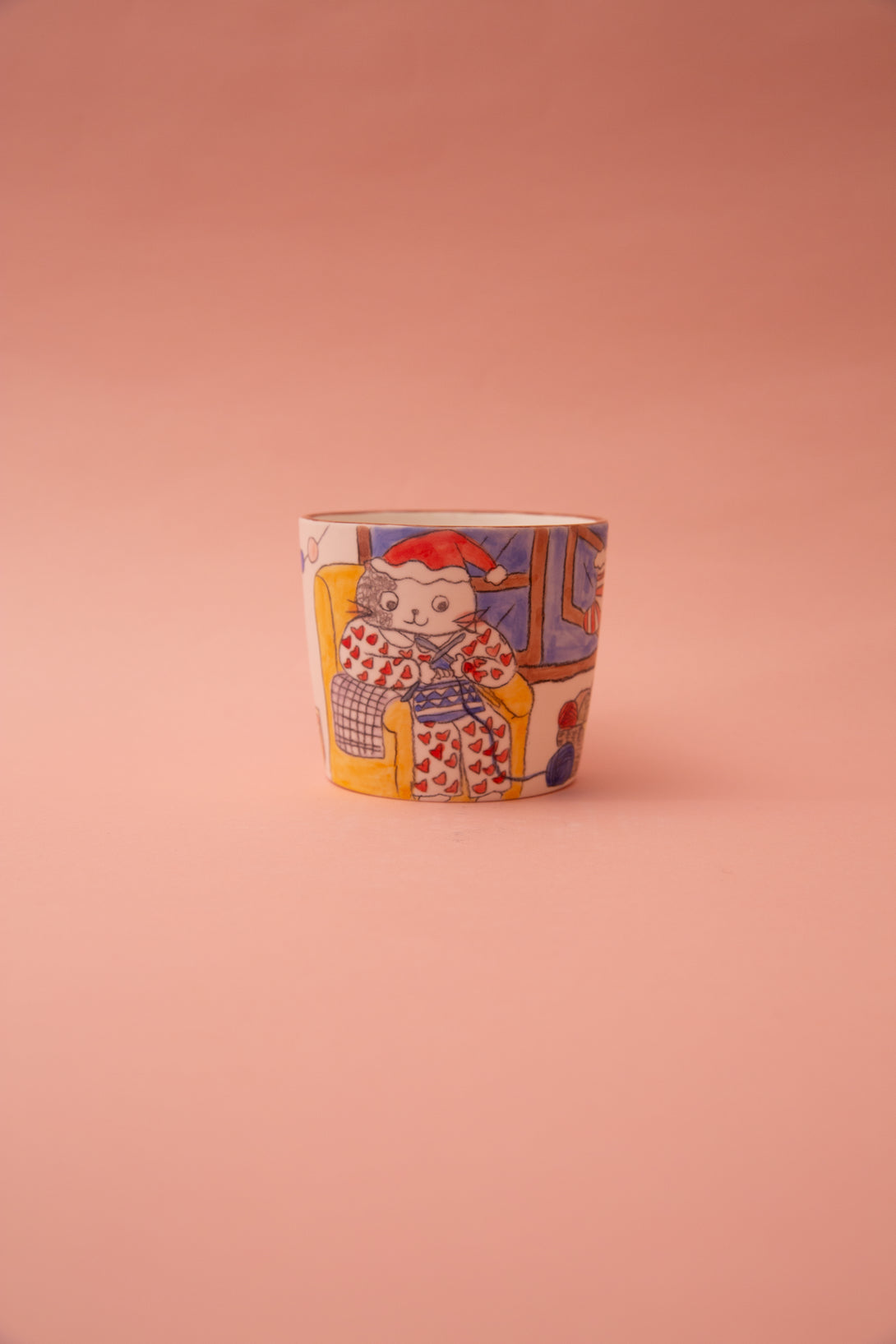 Mug with a colorful design of a cat in a Santa hat on a pink background