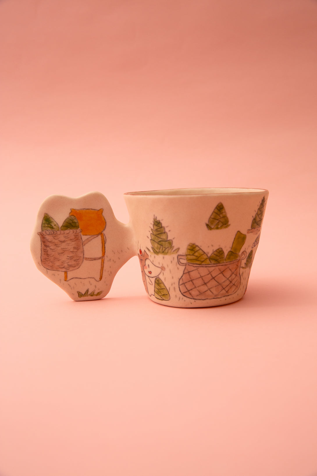 Ceramic cup with a cartoon character and a fun handle design on a pink background