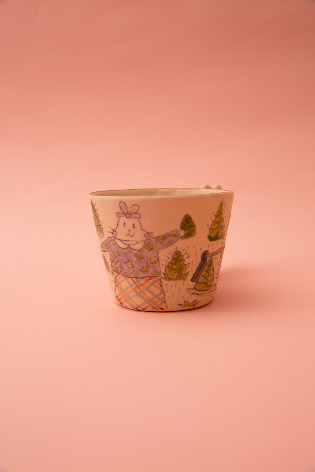 Ceramic mug with a decorative design on a pink background