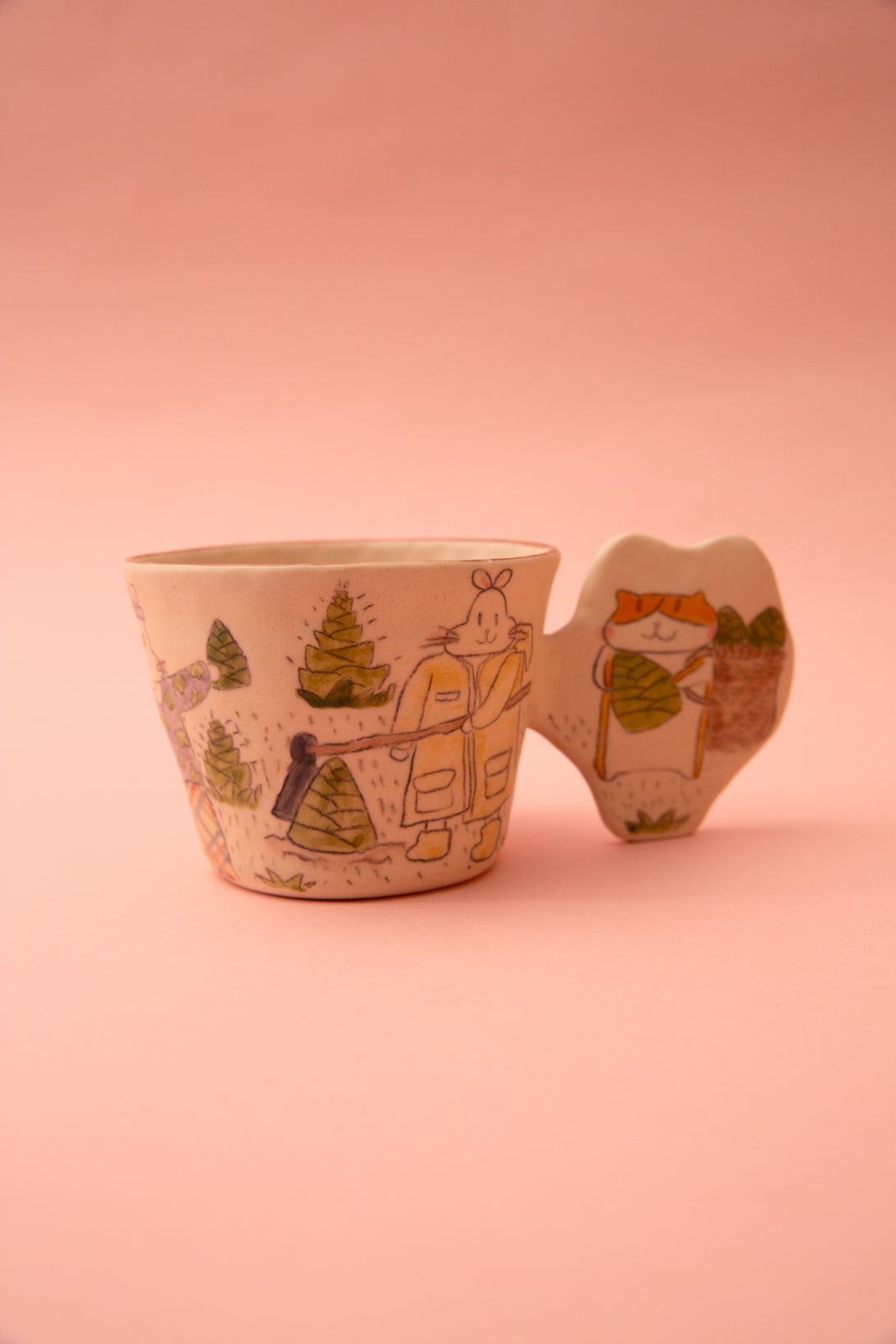 Ceramic cup with a cartoon character and a fun handle design on a pink background