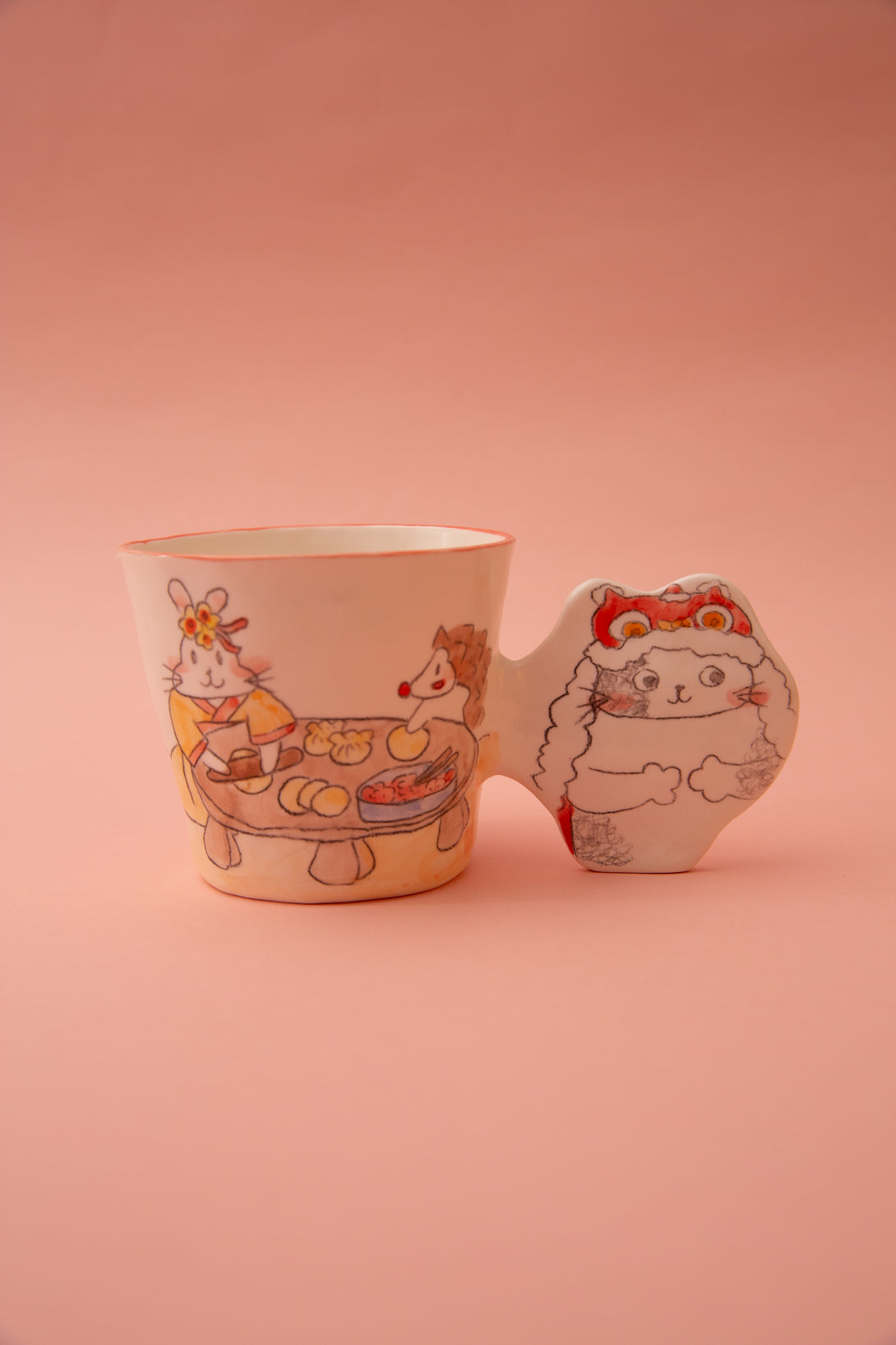 A ceramic mug with animal illustrations and a fun handle on a pink background