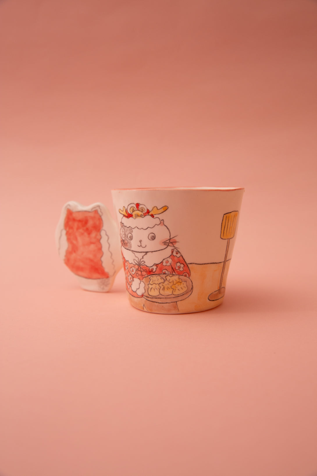 A ceramic mug with animal illustrations and a fun handle on a pink background