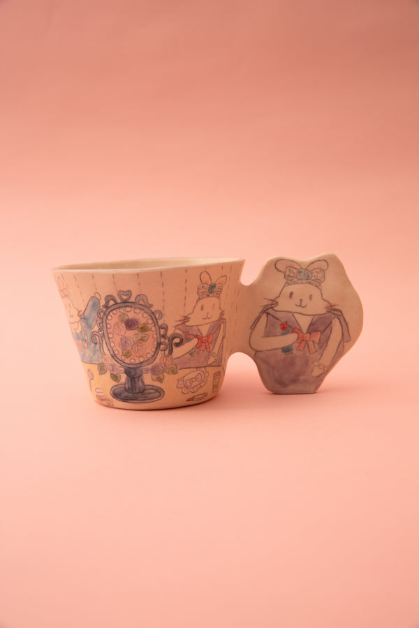 Ceramic cup with artistic designs and a fun handle on a pink background