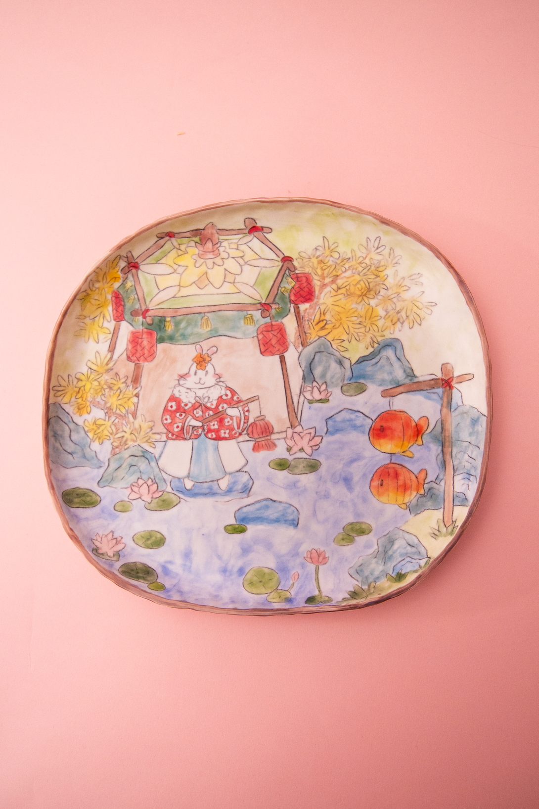 Plate with a colorful design of a traditional scene on a pink background