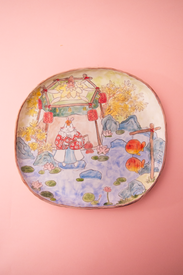 Plate with a colorful design of a traditional scene on a pink background