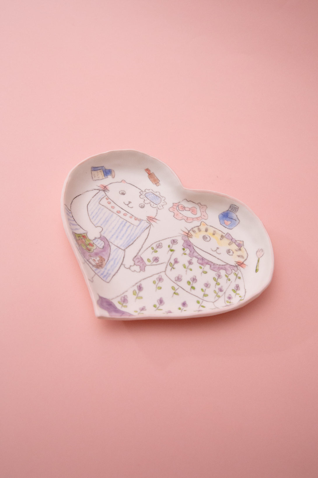 Heart-shaped ceramic tray with illustrations on a pink background