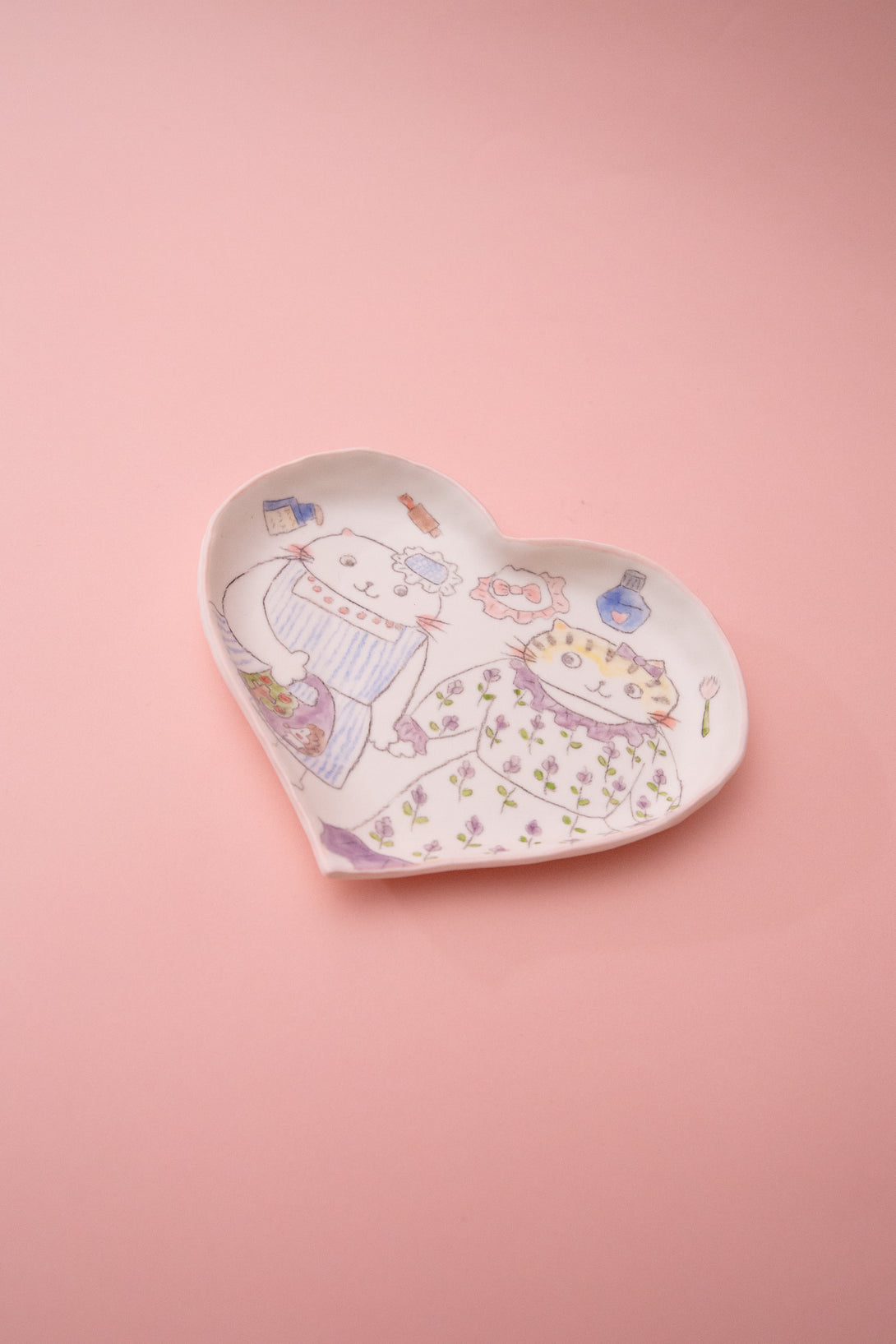 Heart-shaped ceramic dish with illustrations on a pink background