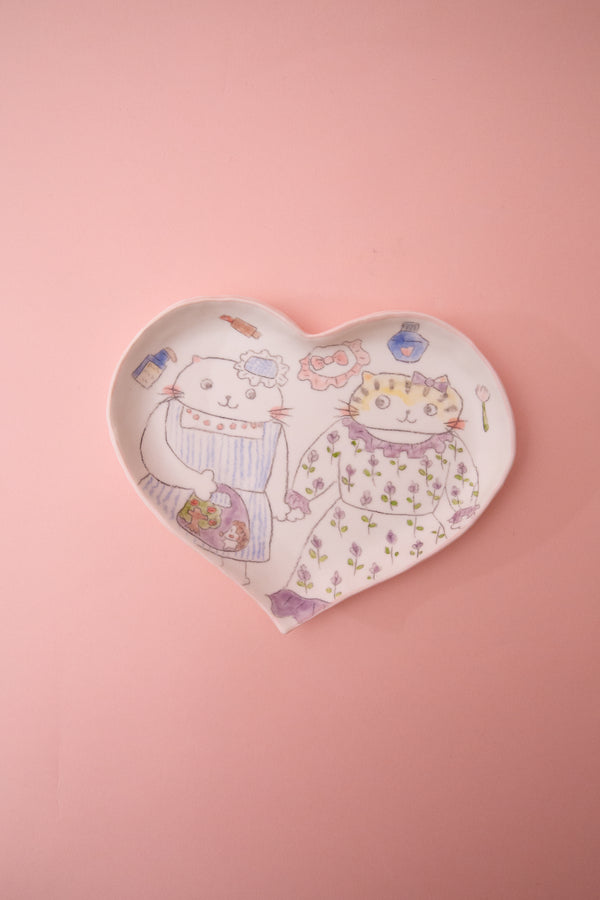 Heart-shaped plate with cartoon designs on a pink background