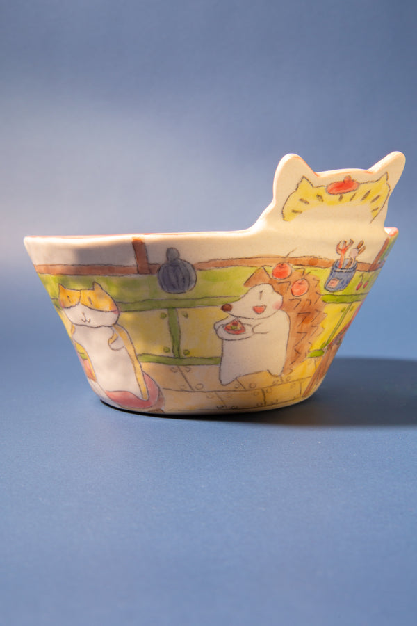 Ceramic bowl with cat-shaped rim on a blue background
