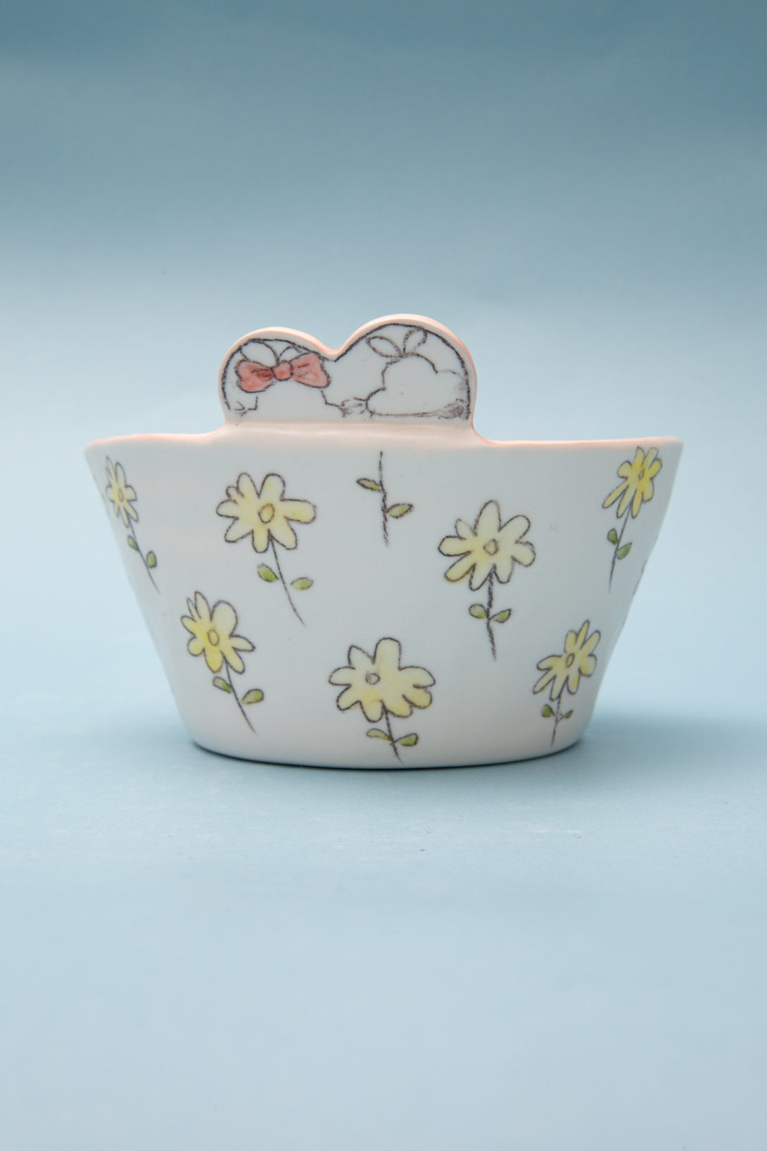 Ceramic bowl with floral design and cartoon character on a light blue background