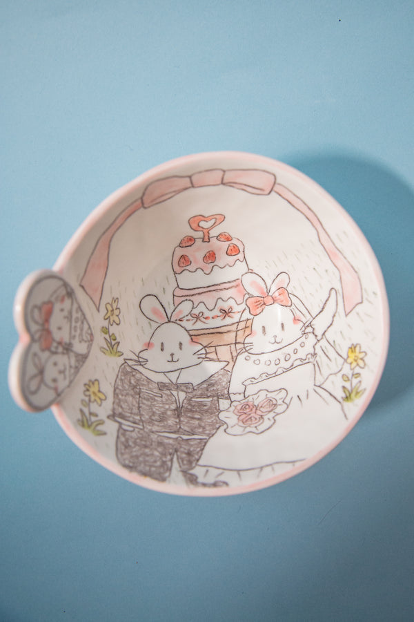 Bowl with cartoon bunnies and a cake on a blue background