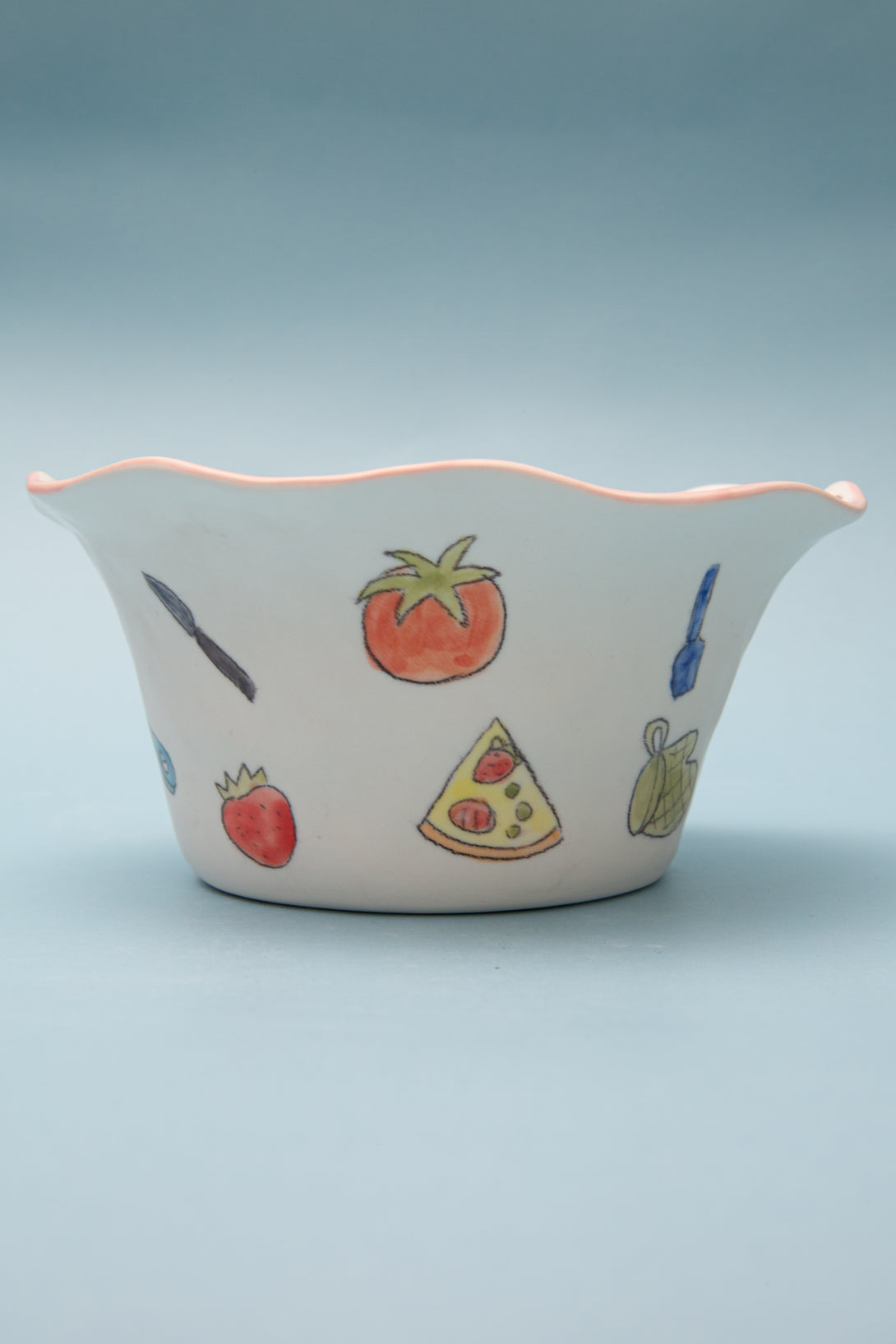 Ceramic bowl with food-themed illustrations on a light blue background