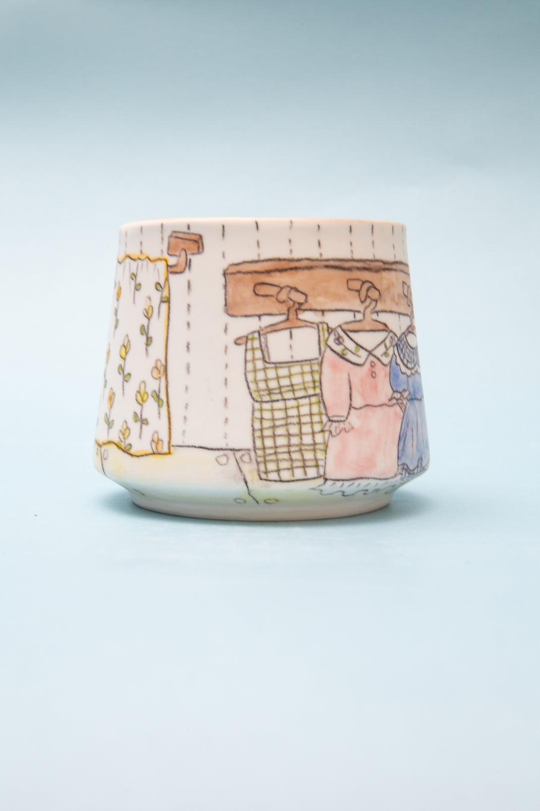 Ceramic cup with a colorful illustration of hanging clothes on a line against a light blue background