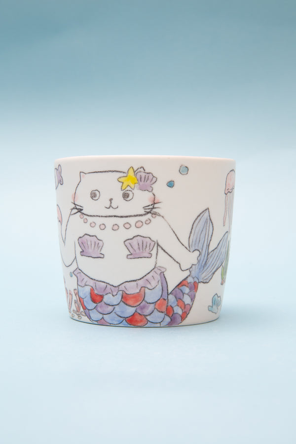 Ceramic mug with a cat mermaid design on a light blue background