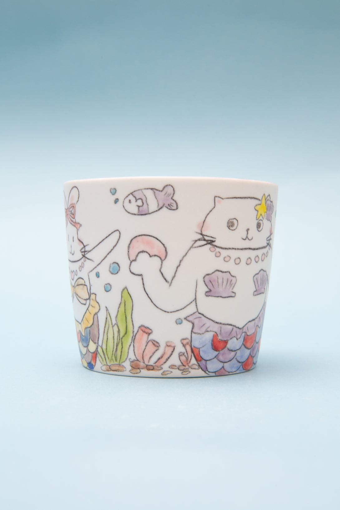 Ceramic mug with a cat-themed design on a light blue background