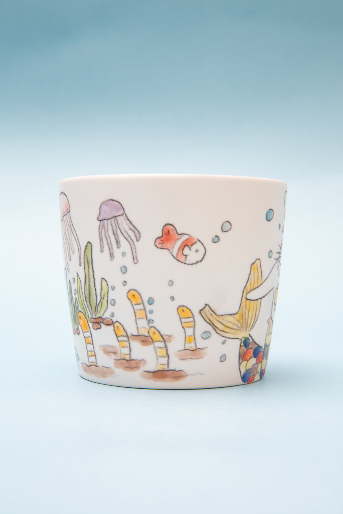 Ceramic mug with underwater scene design on a light blue background