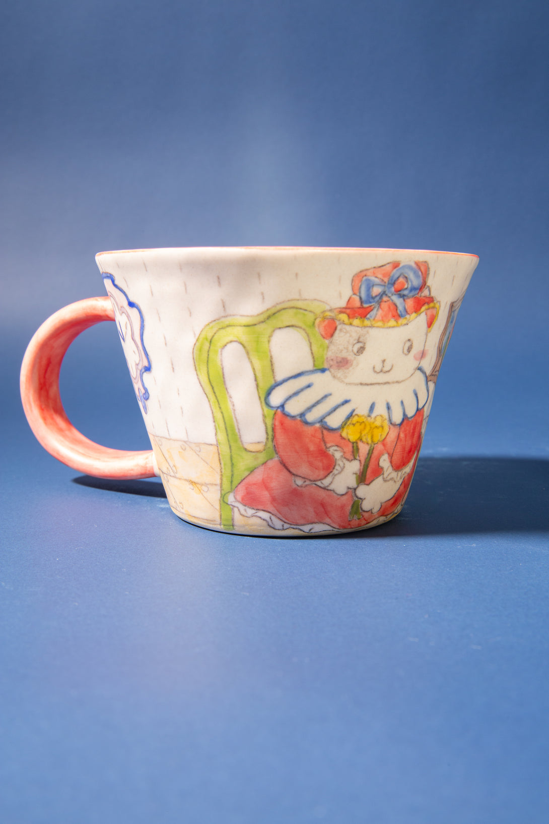 Ceramic mug with a colorful design of a cat on a blue background
