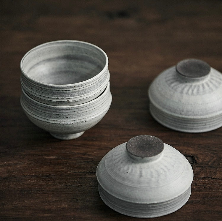 Stacks of gray and white ceramic bowls with a simple design on a wooden table