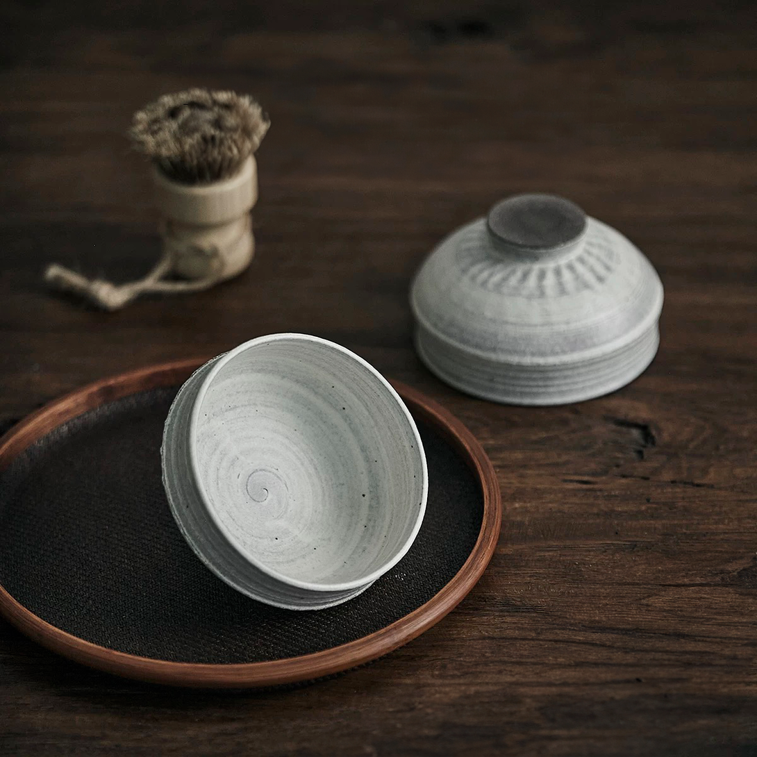 Two white ceramic bowls with a simple design on a wooden tray