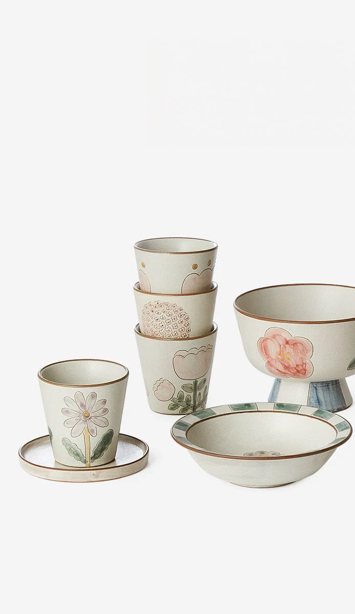 A ceramic cup with floral patterns in green and pink colors on a beige background.