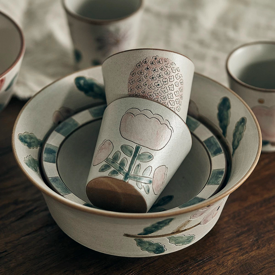 A ceramic cup with floral patterns in green and pink colors