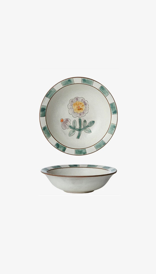 A ceramic bowl with green tile design around the rim and a floral pattern in the center, viewed from the side and top angles.