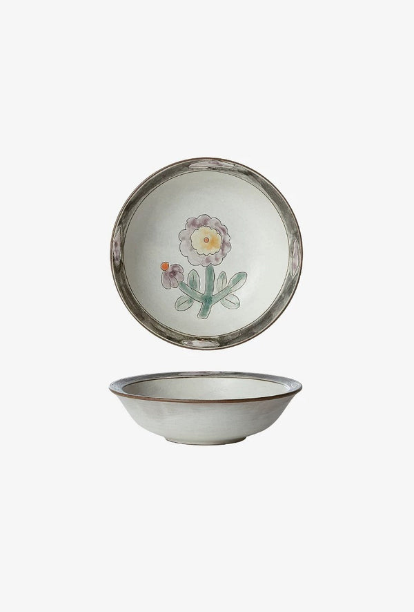 A ceramic bowl with a floral pattern and a decorative element in the center, with a visible green rim.