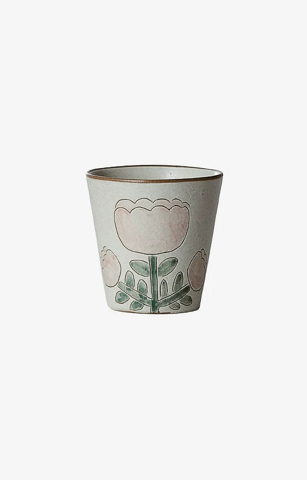 A ceramic cup with floral patterns in green and pink colors on a beige background.