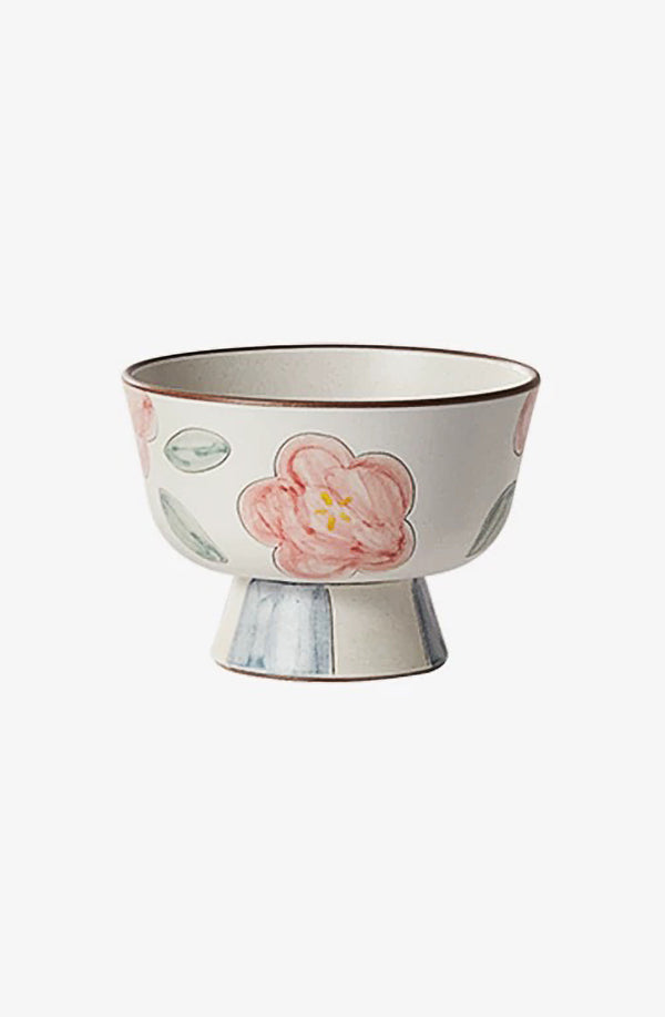 A beige ceramic bowl with a floral pattern and a gold rim.