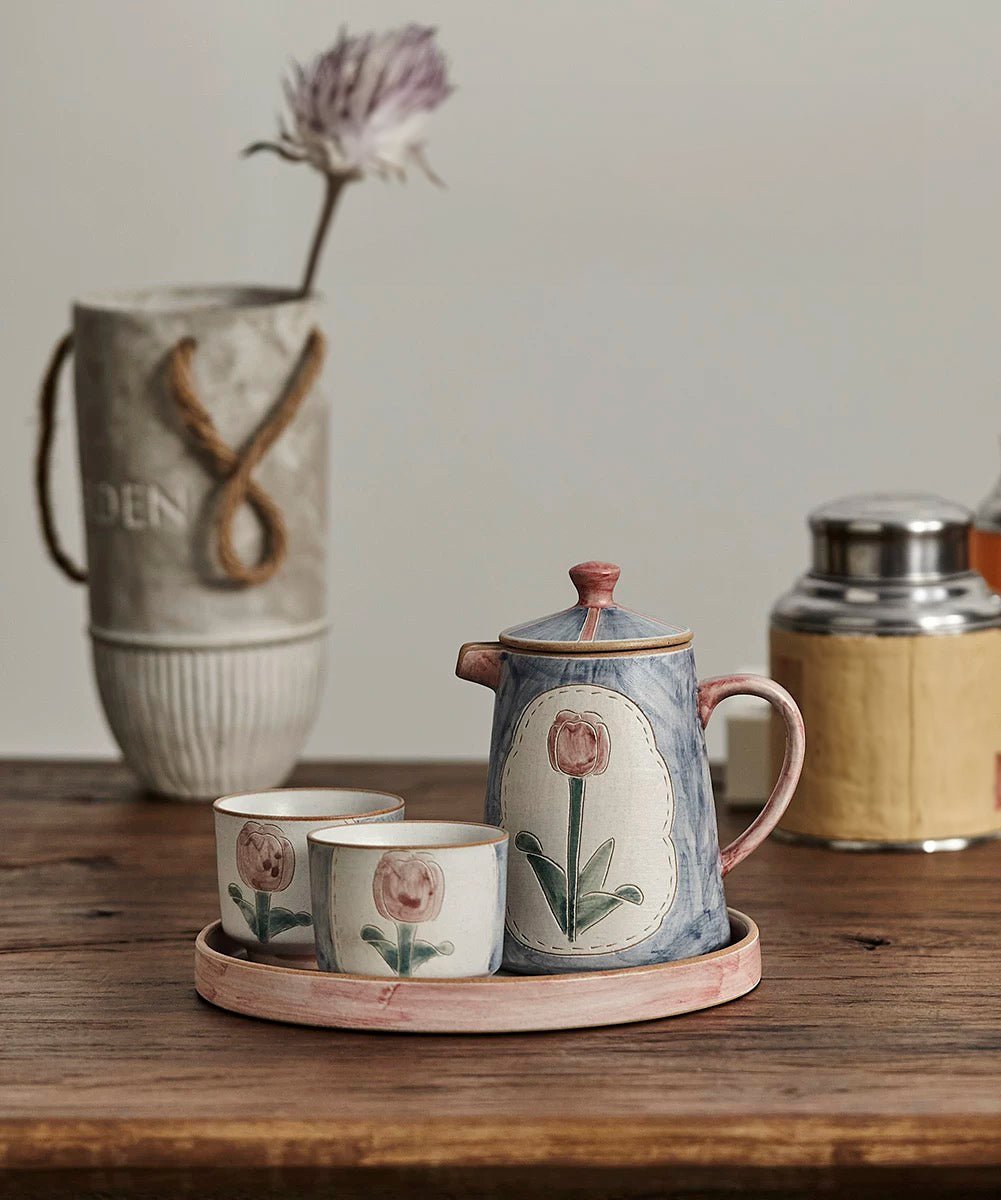 a set of teapot, cup and saucer in floral patterns, primarily in blue and pink colors.
