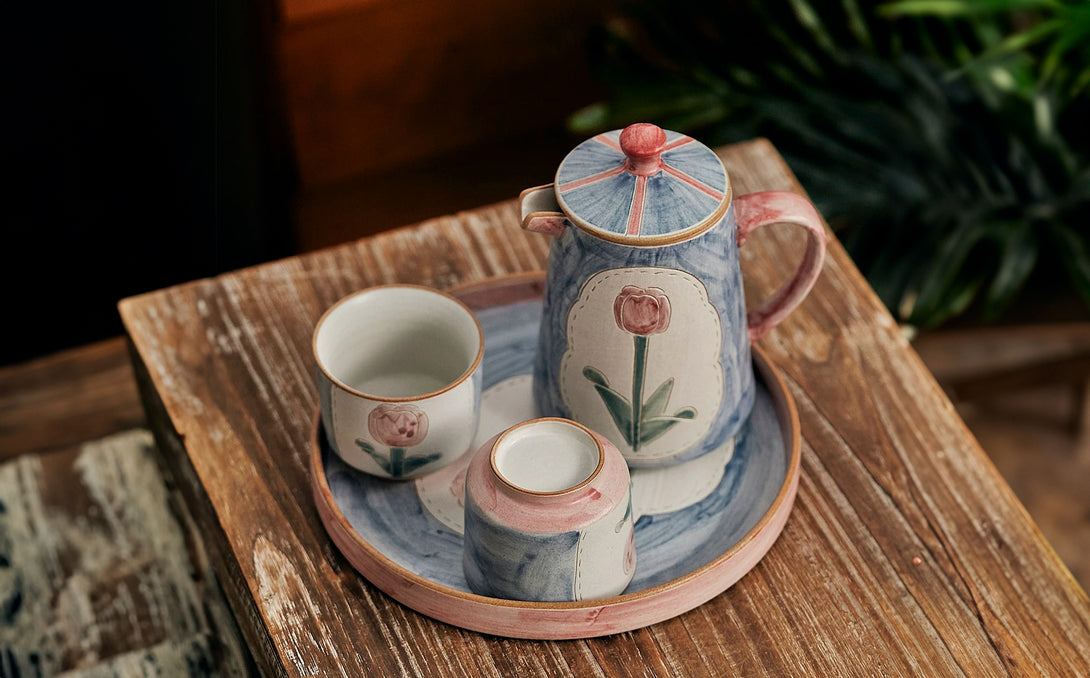 a set of teapot, cup and saucer in floral patterns, primarily in blue and pink colors.